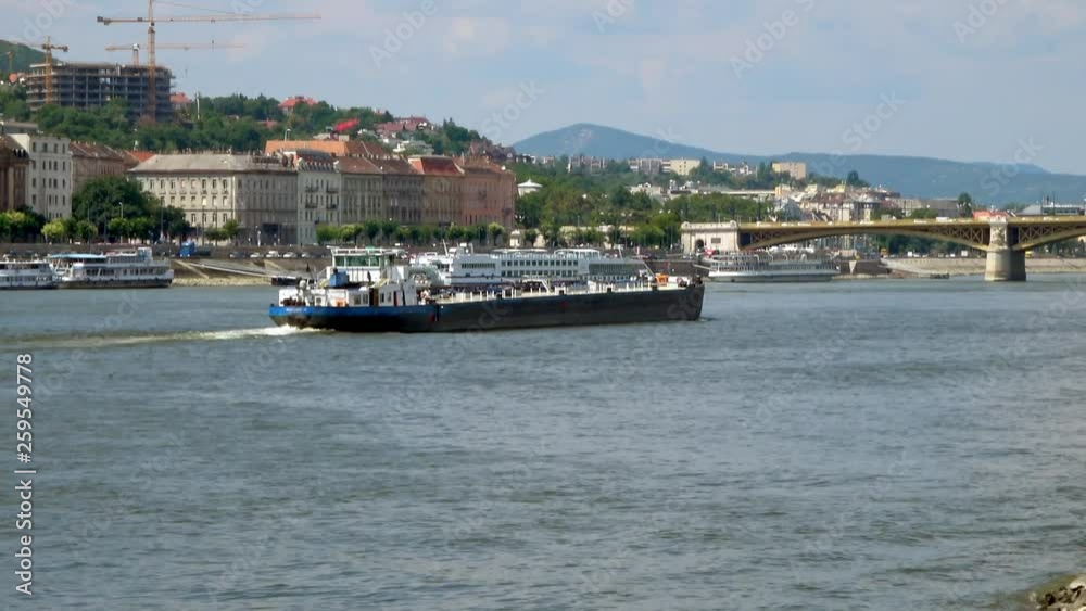 A barge traveling along The Danube between Buda and Pest, Budapest, Hungary on a sunny day. Viewed from Pest side towards Buda. A barge traveling along The Danube between Buda and Pest, Budapest, Hungary on a sunny day. Viewed from Pest side towards Buda.