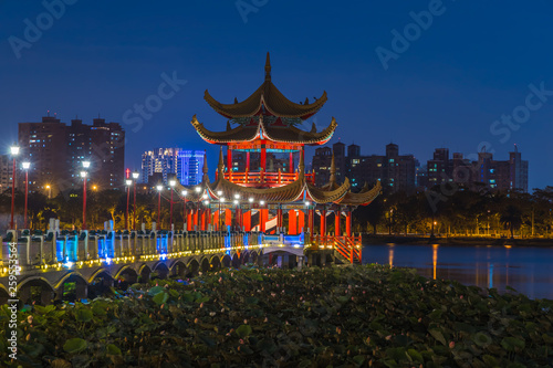 Kaohsiung's famous tourist attractions aerial view, Beautiful decorated traditional Chinese Pagoda with Kaohsiung city in background at night, Wuliting, Kaohsiung, Taiwan.