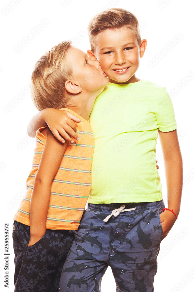 Mother's joy concept. Portrait of two funny siblings brothers posing for picture during family photo shooting: elder boy embraces his little friend. Happy faces, shiny smiles. Studio shot