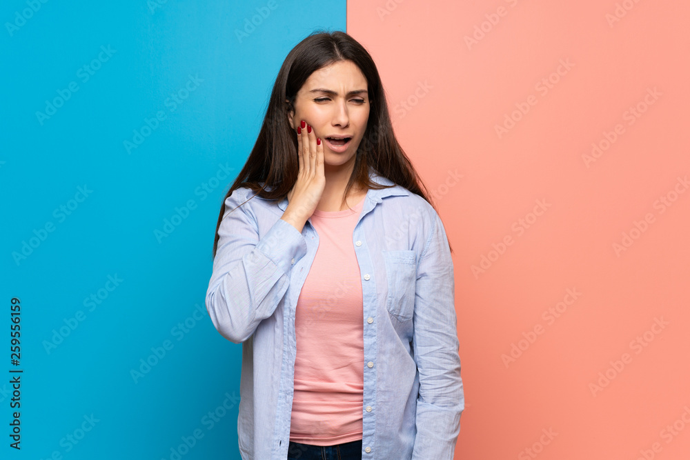 Young woman over pink and blue wall with toothache
