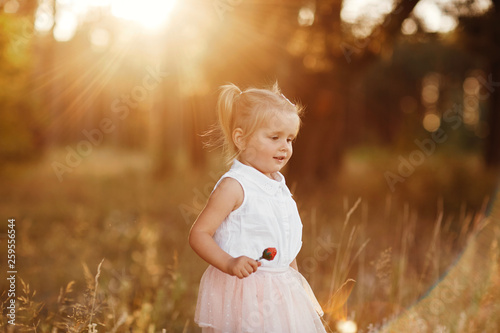 The girl walks in the park at sunset. nice little baby in a pink skirt