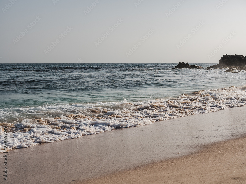 Empty beach against the clear sky and sea waves. Oman, Salalah. Concept of leisure and travel
