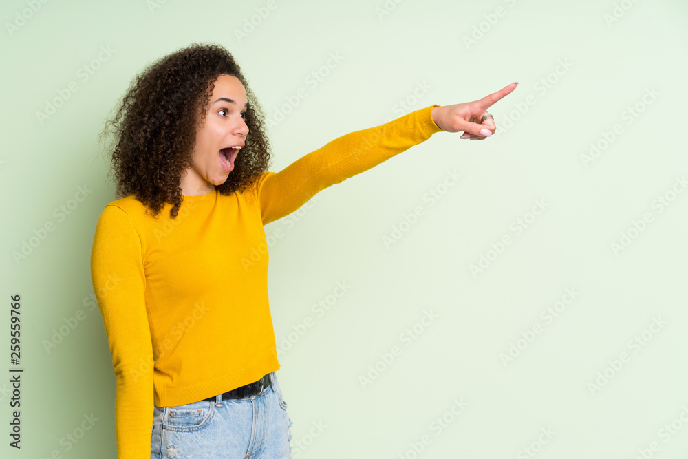 Dominican woman over isolated green background pointing away Dominican woman over isolated green background pointing away