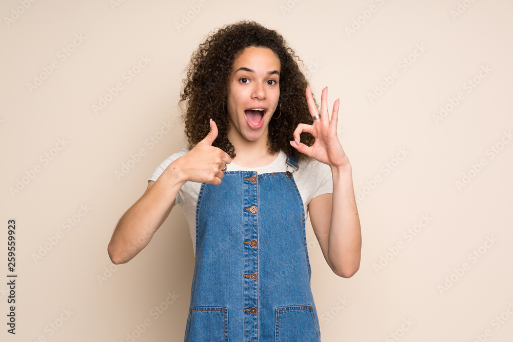 Dominican woman with overalls showing ok sign and thumb up gesture Dominican woman with overalls showing ok sign and thumb up gesture