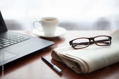 Newspaper with computer on table. Coffee break.