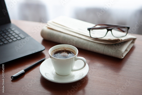 Newspaper with computer on table. Coffee break.