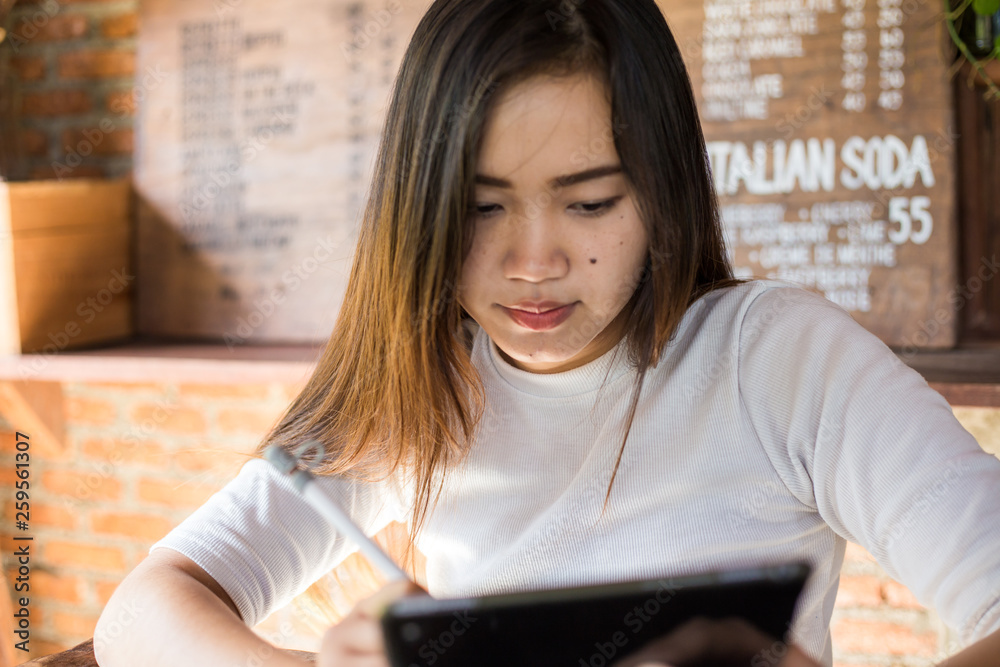 Attractive young asian women use tablet computer in coffee shop Attractive young asian women use tablet computer in coffee shop