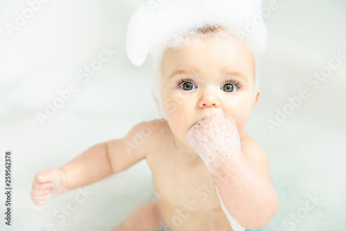 Carta da parati A Baby girl bathes in a bath with foam and soap bubbles