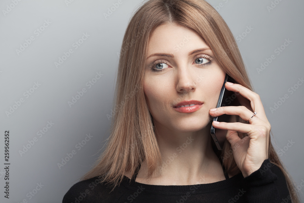 Phone connection concept. Close up portrait of smiling woman with long chestnut hair, natural make-up, speaking using smartphone on light gray background. Copy-space. Studio shot Phone connection concept. Close up portrait of smiling woman with long chestnut hair, natural make-up, speaking using smartphone on light gray background. Copy-space. Studio shot