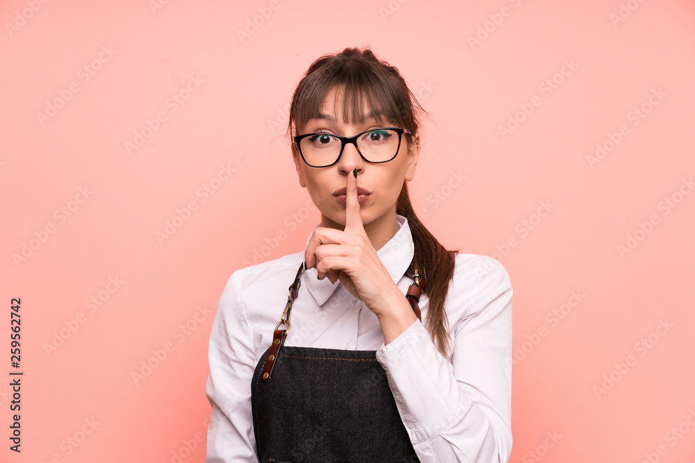 Young waitress over pink background doing silence gesture Young waitress over pink background doing silence gesture