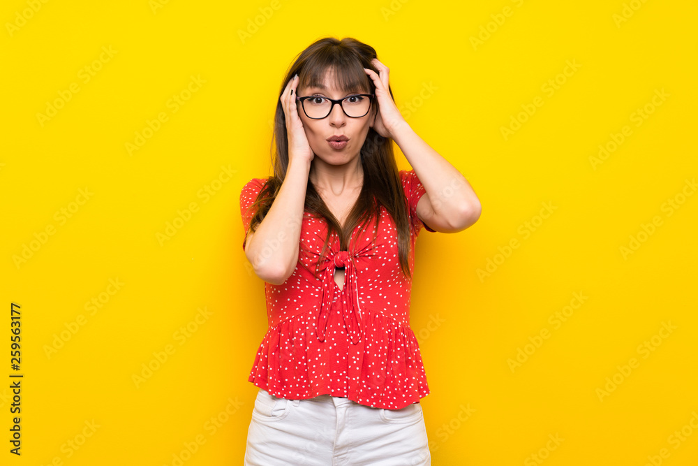 Young woman over yellow wall with surprise expression Young woman over yellow wall with surprise expression