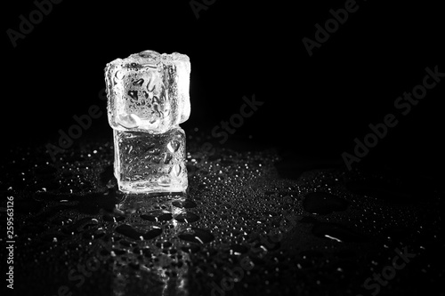 ice cubes reflection on black table background. © peterkai