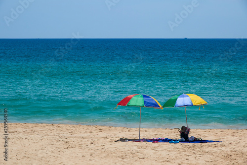 Two colorful umbrellas on white sand beach.