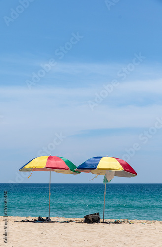 Fototapeta Naklejka Na Ścianę i Meble -  Two colorful umbrellas on white sand beach.