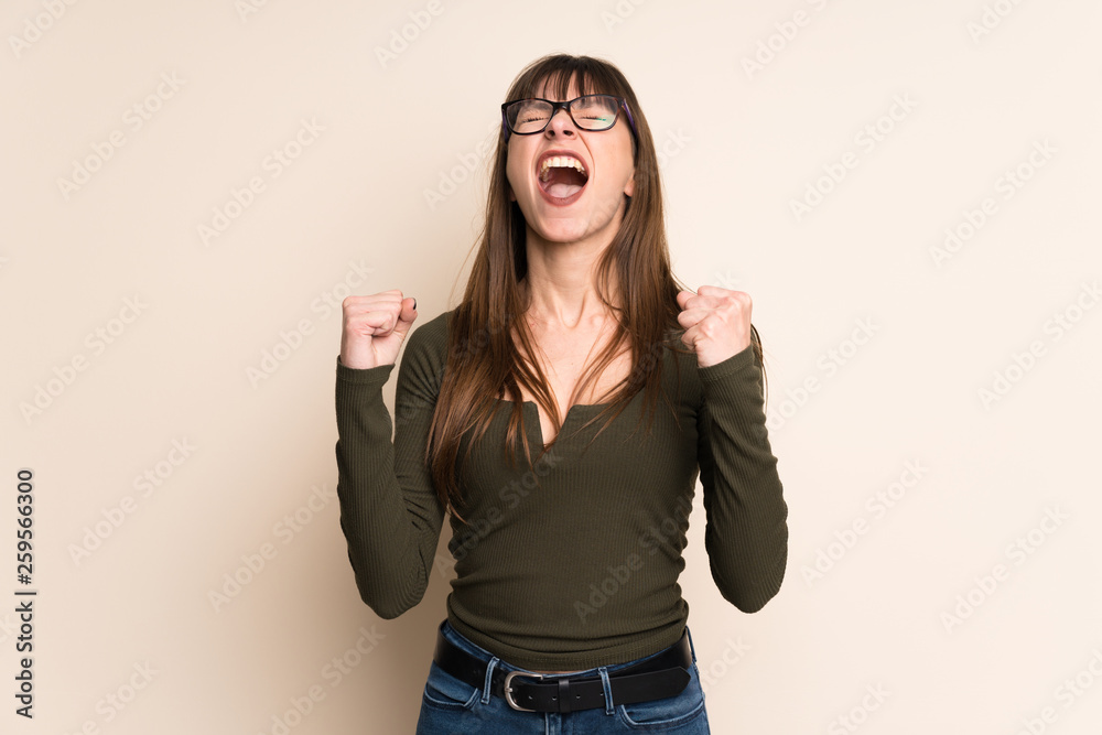 Young woman on ocher background celebrating a victory in winner position Young woman on ocher background celebrating a victory in winner position