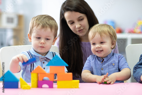 Preschool teacher and cute kids play in kindergarten