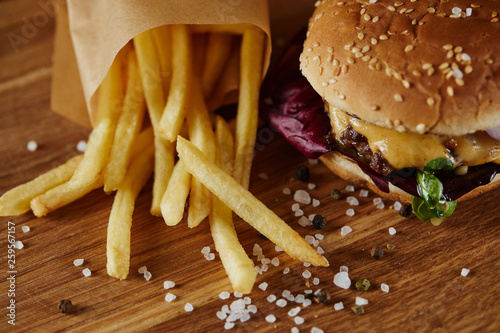salt, french fries and delicious burger with meat on wooden surface