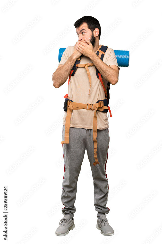 Hiker man covering mouth and looking to the side over isolated white background Hiker man covering mouth and looking to the side over isolated white background