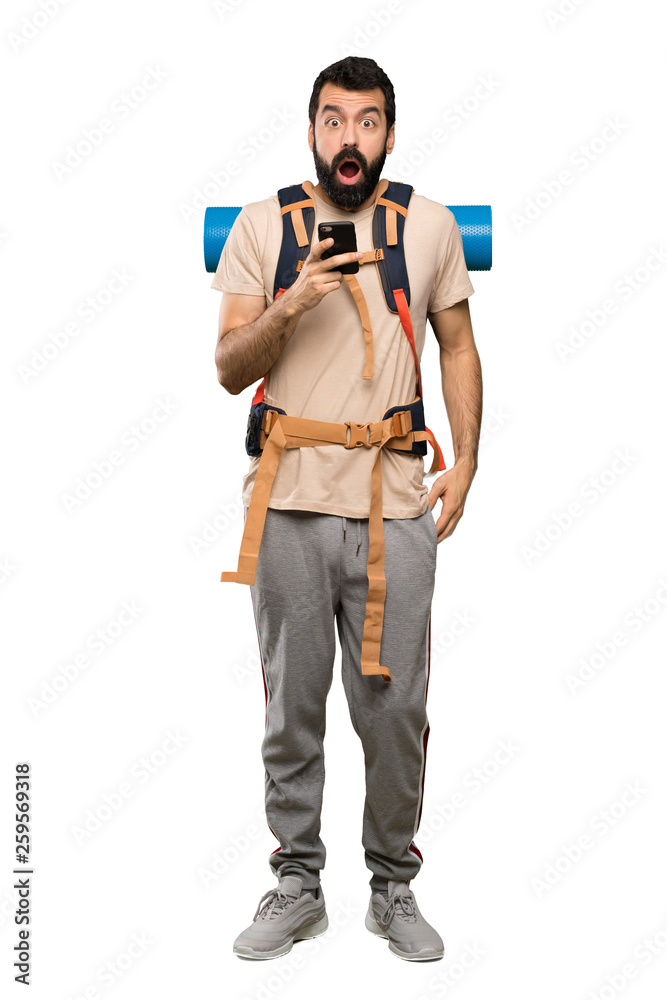 Hiker man surprised and sending a message over isolated white background Hiker man surprised and sending a message over isolated white background