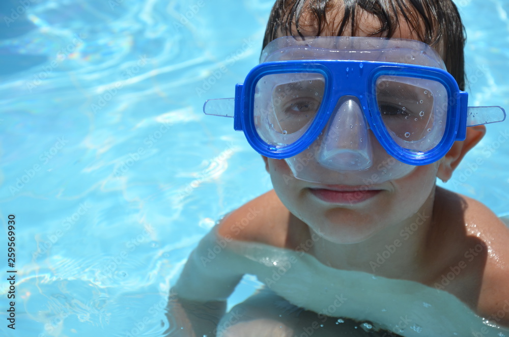 Naklejka premium Teenager boy wearing mask swimming in the pool. Happy holiday concept. Cute happy little boy swimming and snorking in the sea ocean in crystal blue water