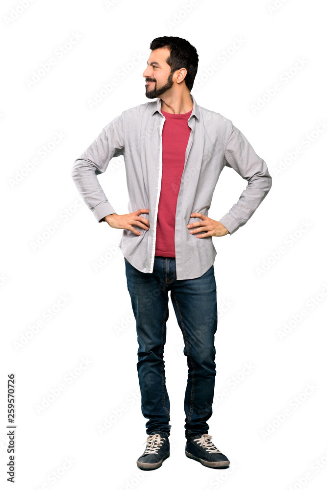 Full-length shot of Handsome man with beard posing with arms at hip and smiling over isolated white background Full-length shot of Handsome man with beard posing with arms at hip and smiling over isolated white background