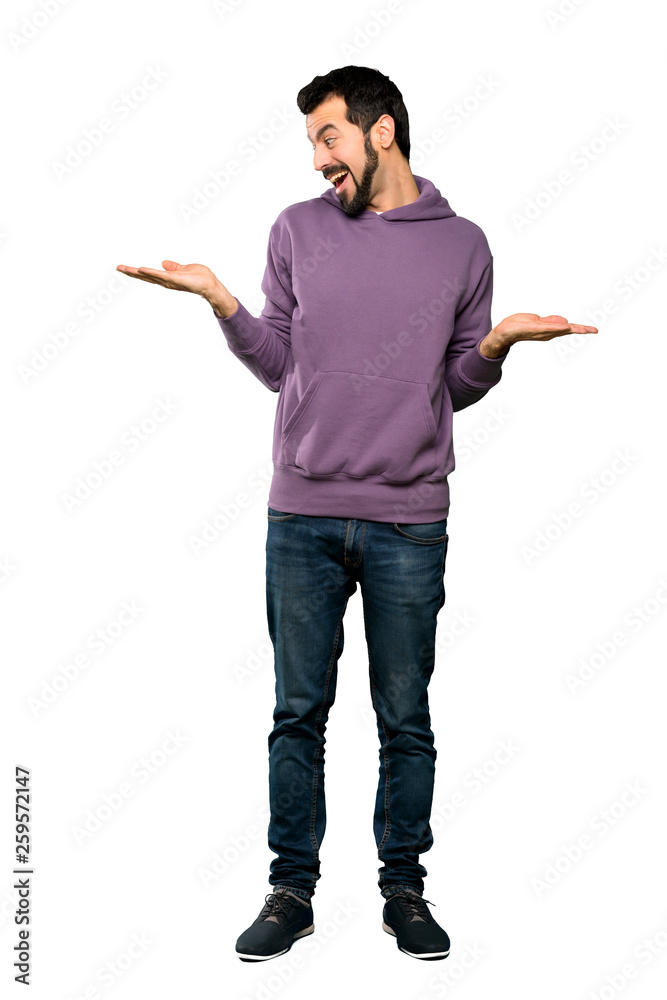 Full-length shot of Handsome man with sweatshirt holding copyspace with two hands over isolated white background Full-length shot of Handsome man with sweatshirt holding copyspace with two hands over isolated white background