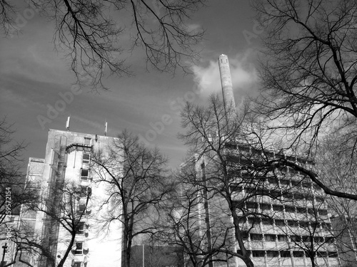 Bäume mit kargen Ästen und Bürogebäude der Goethe Universität im Sonnenschein im Stadtteil Bockenheim am Westend in Frankfurt am Main, fotografiert in neorealistischem Schwarzweiß photo