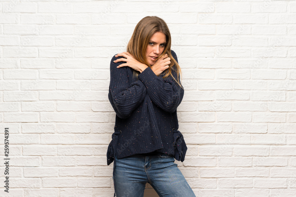 Blonde woman over brick wall freezing Blonde woman over brick wall freezing