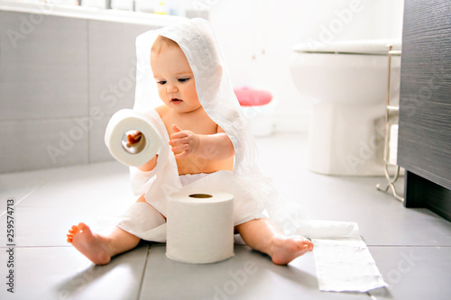 Toddler ripping up toilet paper in bathroom photo