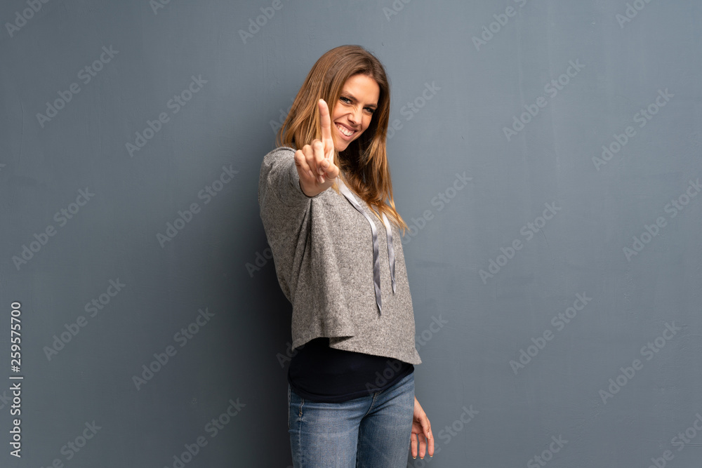 Blonde woman over grey background showing and lifting a finger Blonde woman over grey background showing and lifting a finger