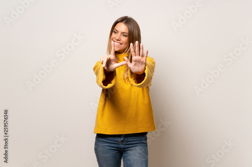 Woman with yellow sweater over isolated wall counting seven with fingers
