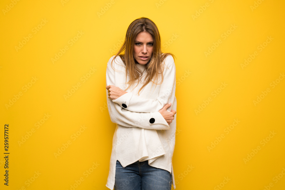Fototapeta premium Blonde woman over yellow wall freezing