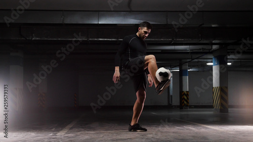A young soccer man training the basic tricks with the ball Balancing the ball on the lifted feet