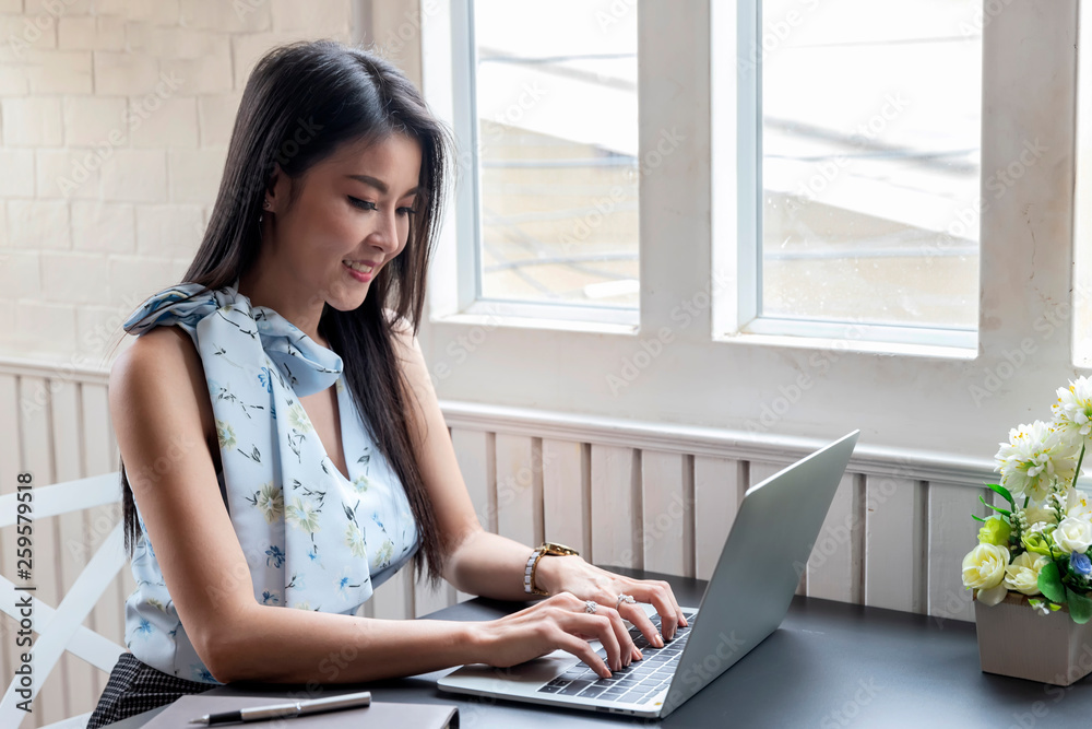 Businesswoman working with laptop computer while sitting near window in creative office or cafe. Businesswoman working with laptop computer while sitting near window in creative office or cafe.