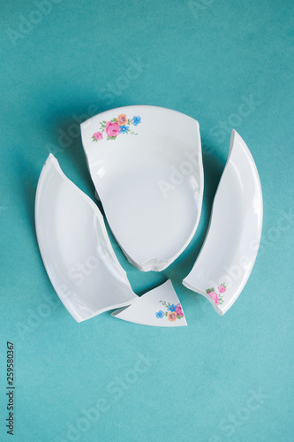 broken white plate on blue background, copy space, top view