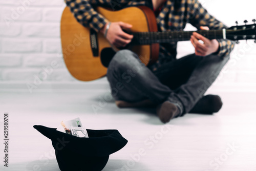 hat with money on the background of a man with a guitar, the concept of earnings and poverty photo