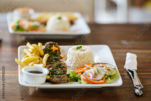 grilled beef steak served on plate withh rice, salad and frites. Selective focus photography