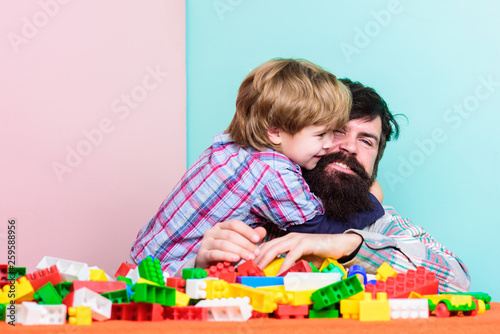 Father and son create constructions. Bearded man and son play together. Surefire ways to bond with your son. Father son game. Dad and kid build plastic blocks. Child care development and upbringing photo