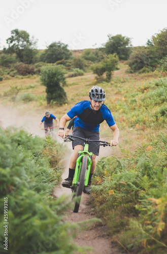 Mountain Biker Enjoying Dusty Summer Trail With Friends
