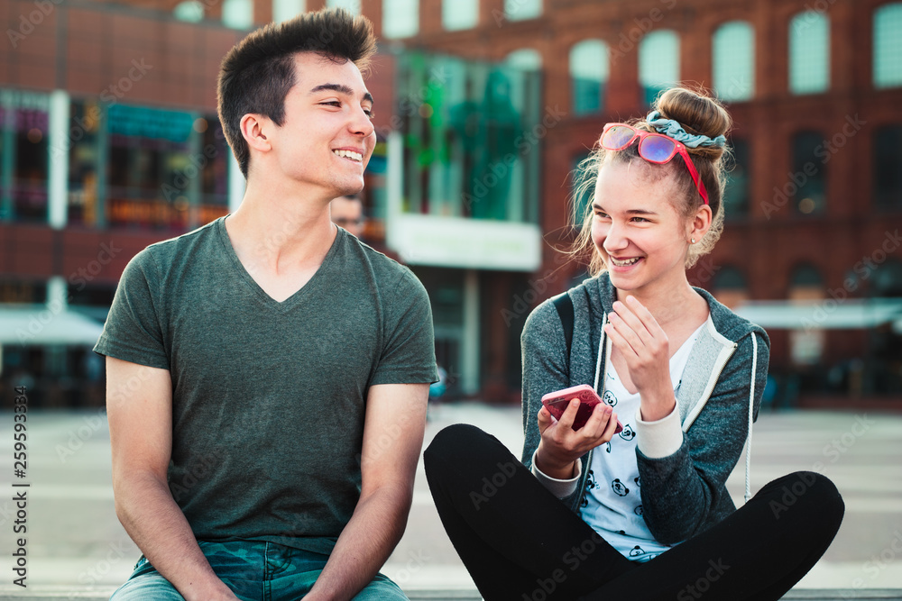 Φωτογραφία Couple of friends, teenage girl and boy,  having fun together with smartphones