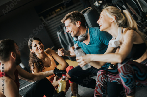 Friends in sportswear talking and laughing together while resting in the gym after a workout