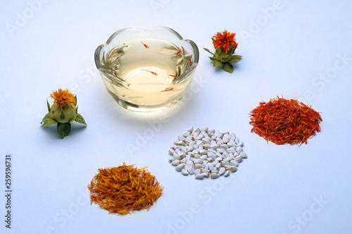 Flowering and saffron flowers. Seeds for home garden. Carthamus tinctorius safflower. Spices and cosmetic oil from safflower on a white background.