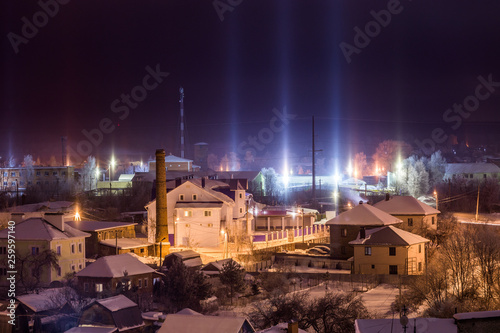 night winter cityscape with light pillars atmospheric phenomenon photo
