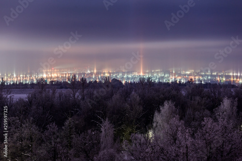 night winter cityscape with light pillars atmospheric phenomenon photo