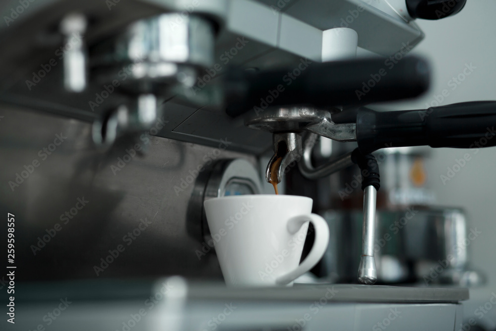 Coffee machinne pours freshly brewed coffee in white cup Coffee machinne pours freshly brewed coffee in white cup