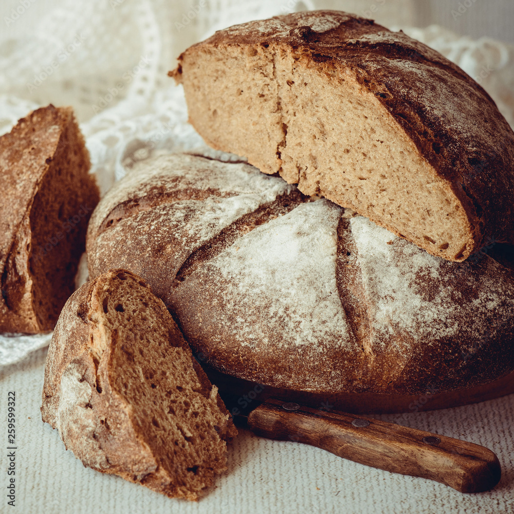 Fotografie Freshly baked homemade rye bread on a round wooden board on an old table
