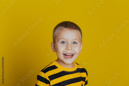 Portrait of an attractive smiling boy with in a striped sweater on a yellow background