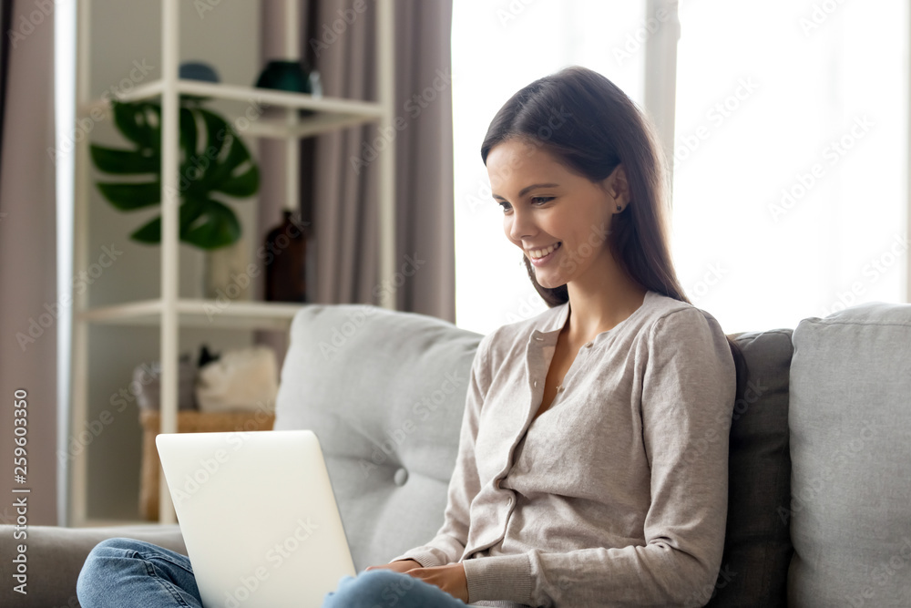 Young woman using laptop relaxing on sofa at home Young woman using laptop relaxing on sofa at home