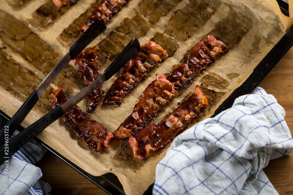 Knusprig gebratene Bacon Speck Scheiben aus dem Ofen auf Backblech mit Backpapier mit