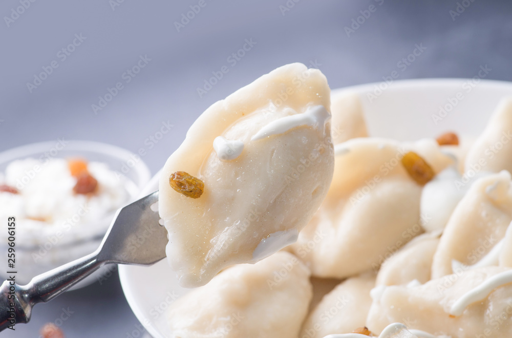 boiled sweet dumplings with filling and sauce on a fork on the background of a full plate boiled sweet dumplings with filling and sauce on a fork on the background of a full plate